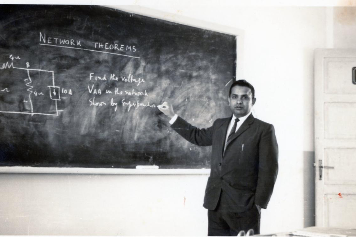Enam teaching electrical engineering at a chalkboard.